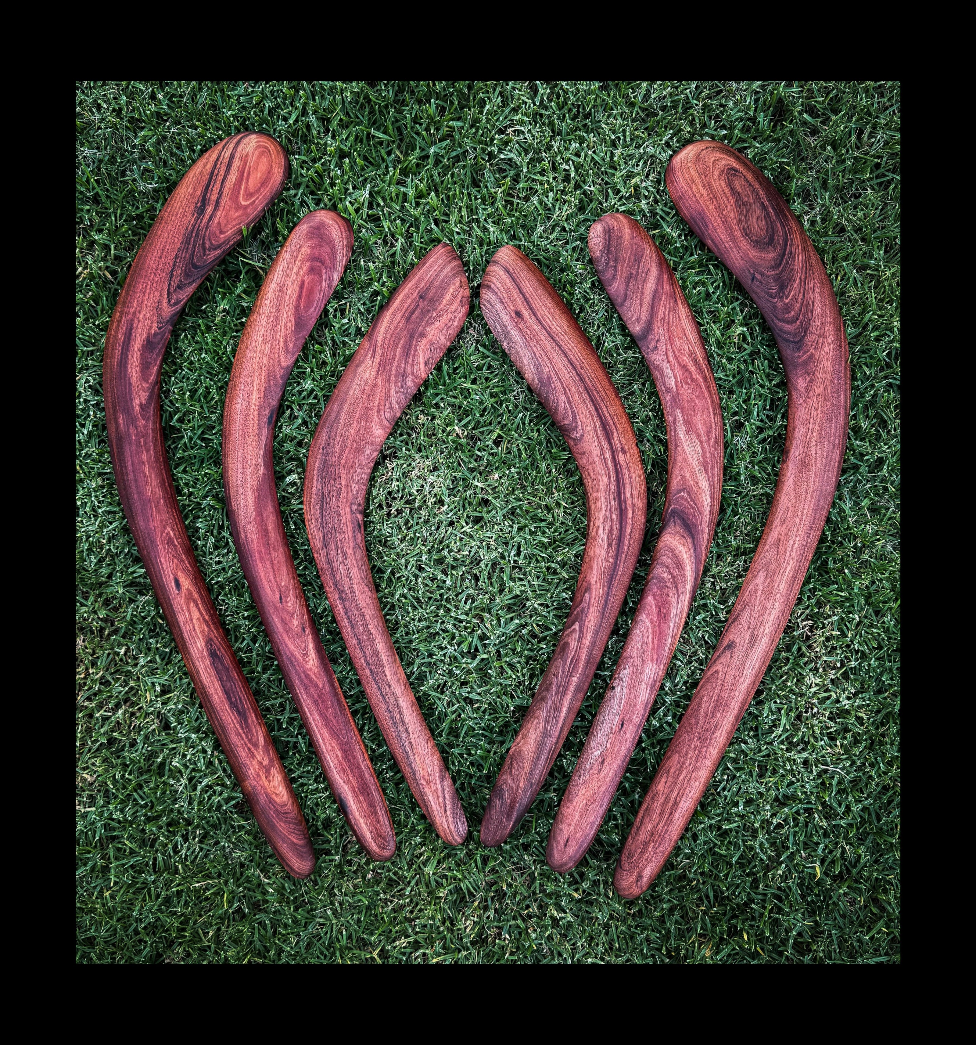 Set of six wooden boomerangs on a grassy background